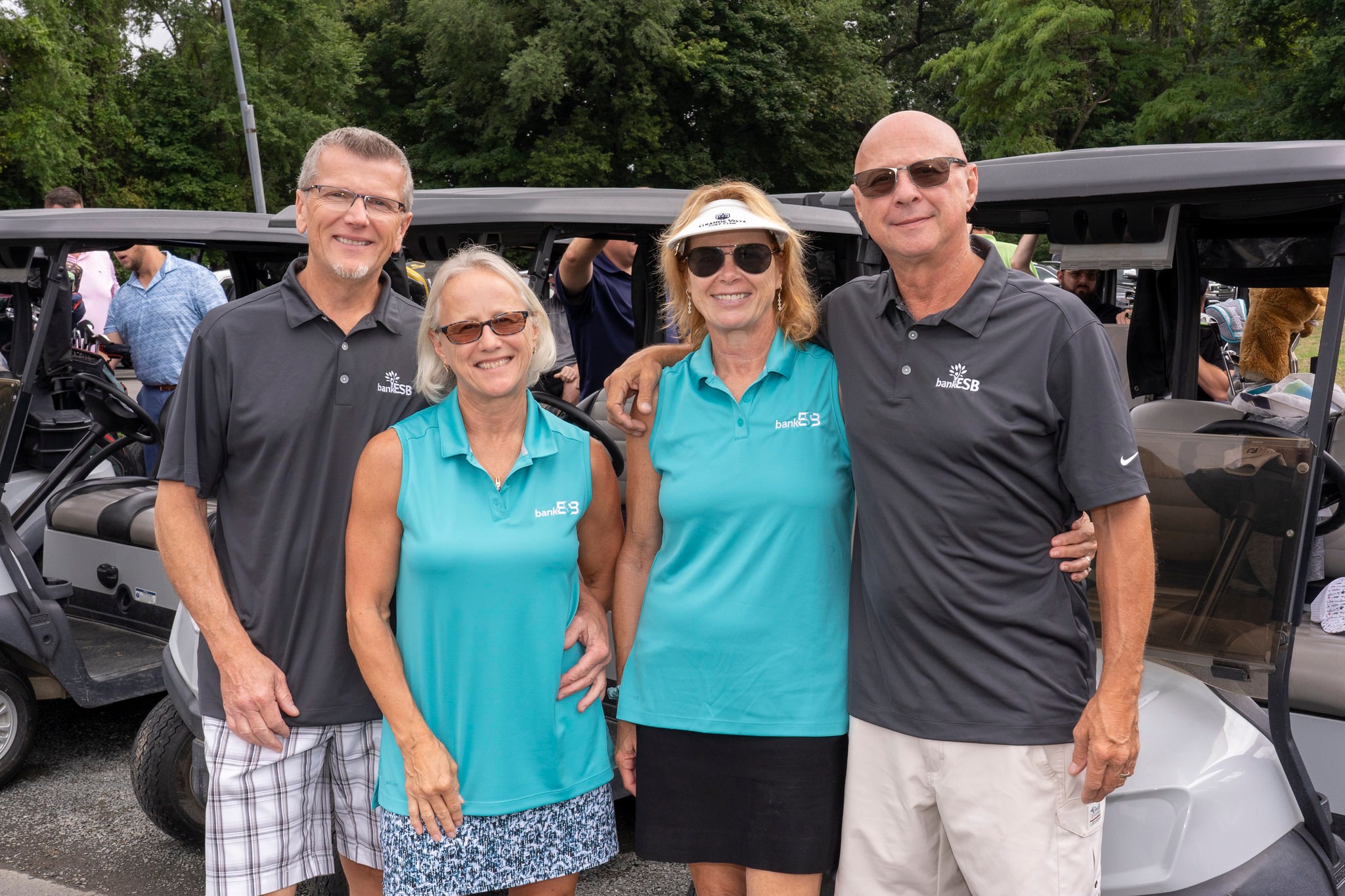 Two women and two men in golf shorts and tees, smiling